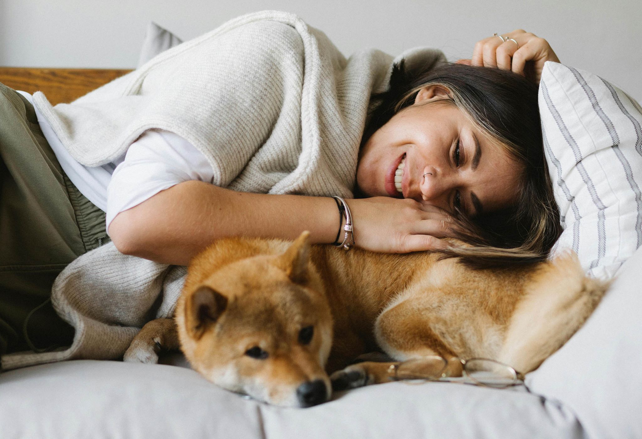 A woman cuddles with a small dog on a light colored couch