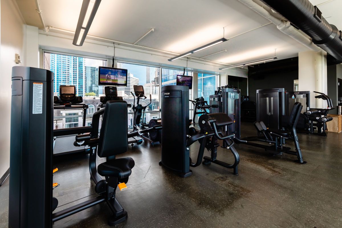The Vue Charlotte fitness center featuring cardio equipment and strength machines facing floor to ceiling windows looking out onto Charlotte cityscape