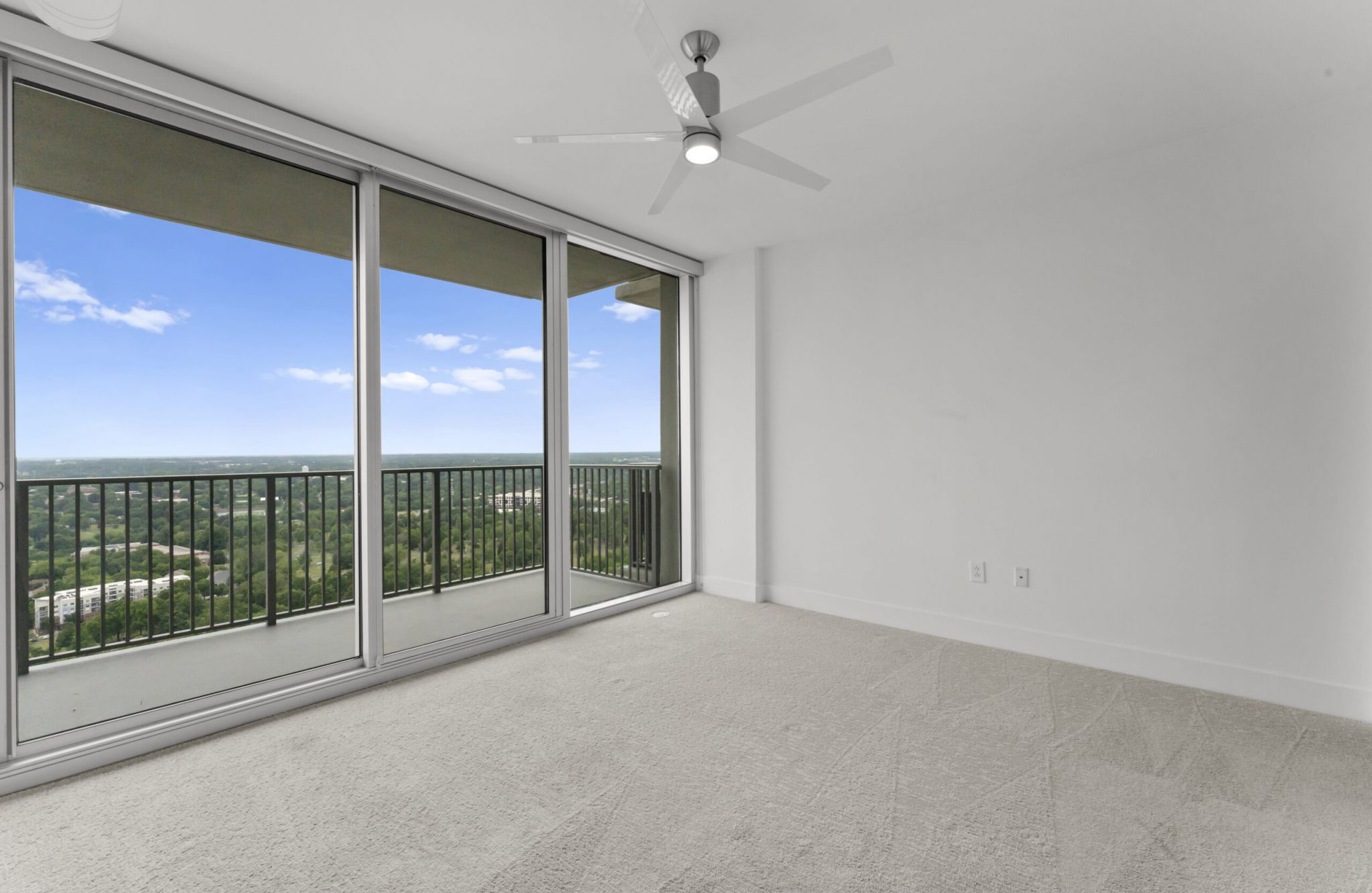 The Vue at Charlotte, NC apartment bedroom with large bed, carpet, dresser, and large full-height windows