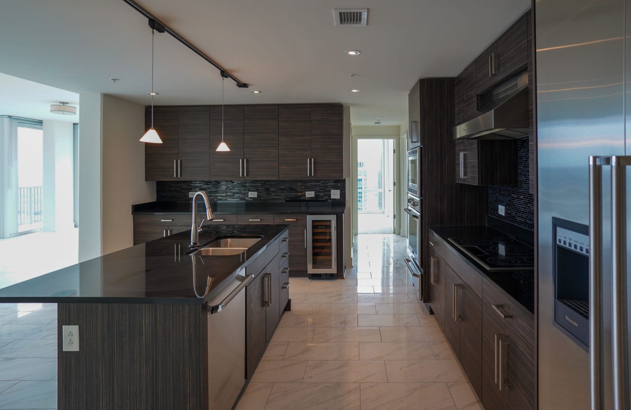 The Vue at Charlotte, NC apartment with large open-space concept kitchen, a kitchen island with stainless steel sink, granite slab countertops, and abundant custom cabinets floor to ceiling