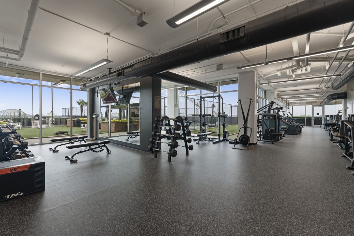 The Vue Charlotte fitness center featuring cardio equipment and strength machines facing floor to ceiling windows looking out onto Charlotte cityscape