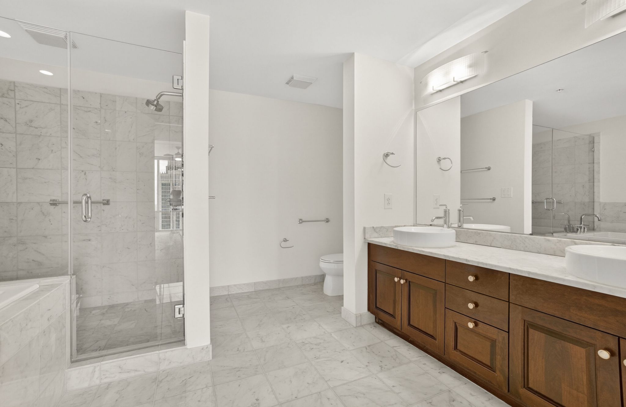 The Vue at Charlotte, NC luxury apartment bathroom with glass-enclosed shower with tile and large soaking tub