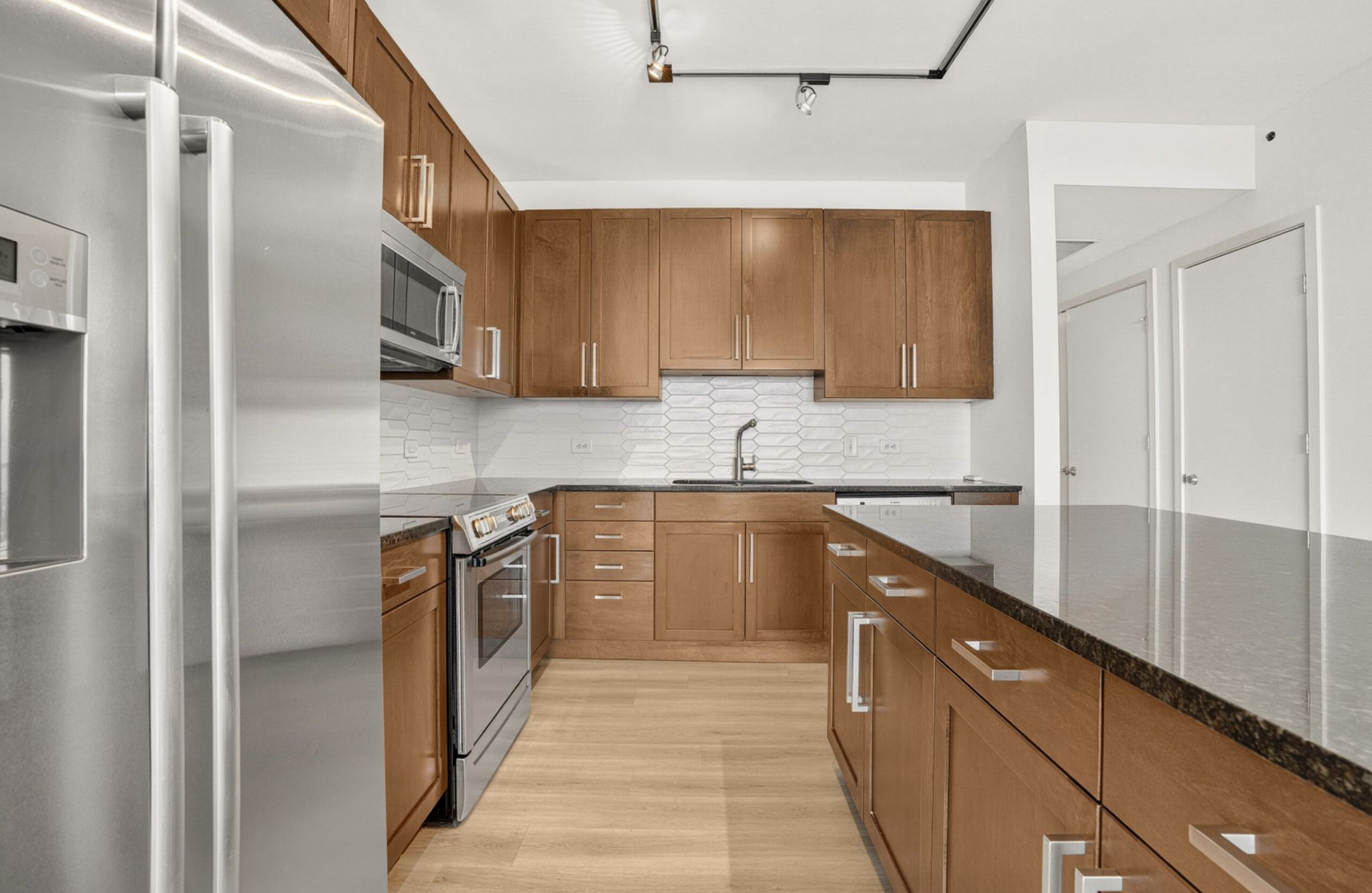 The Vue at Charlotte, NC apartment with large open-space concept kitchen, a kitchen island with stainless steel sink, granite slab countertops, and abundant custom cabinets floor to ceiling